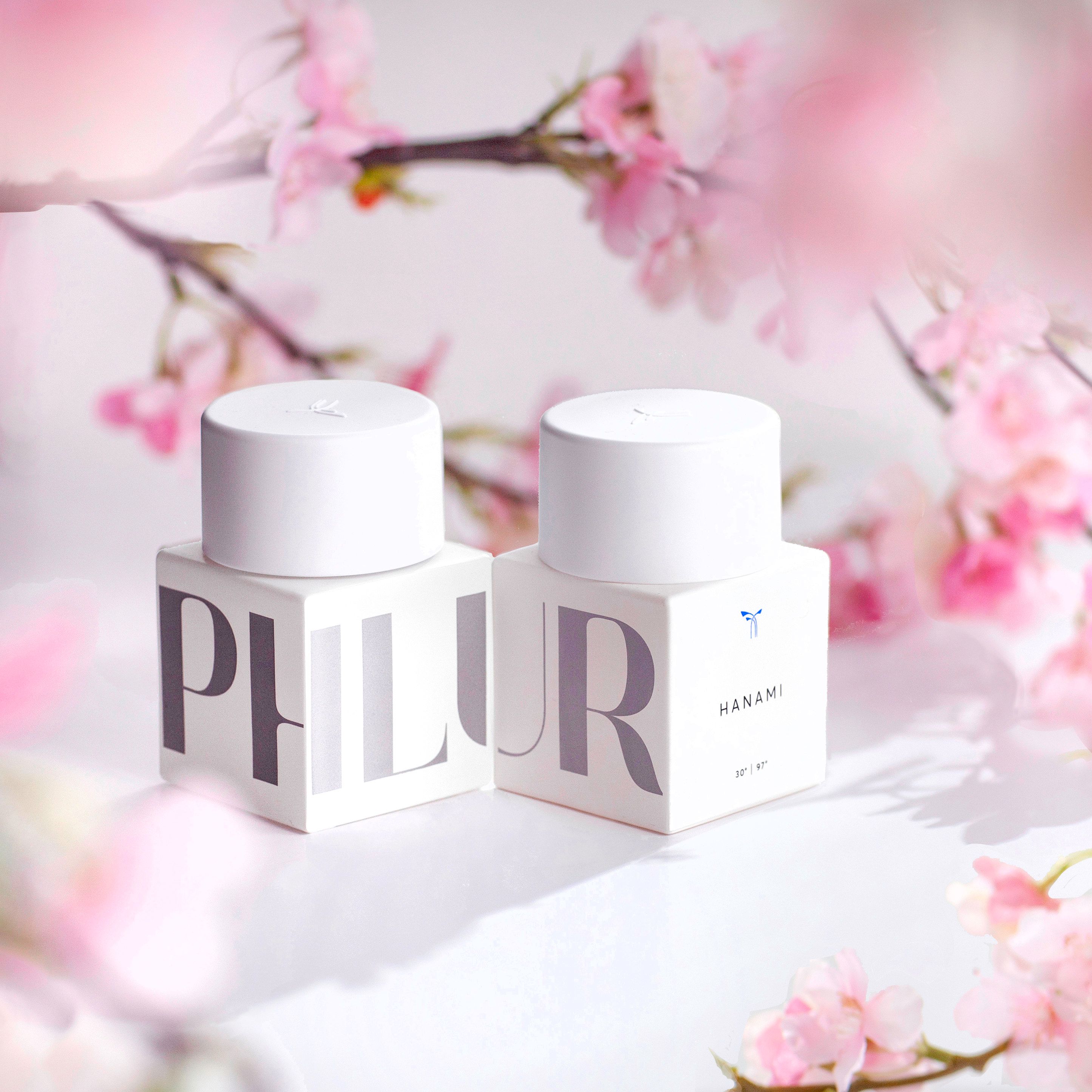 2 white bottles of phlur with cherry blossoms