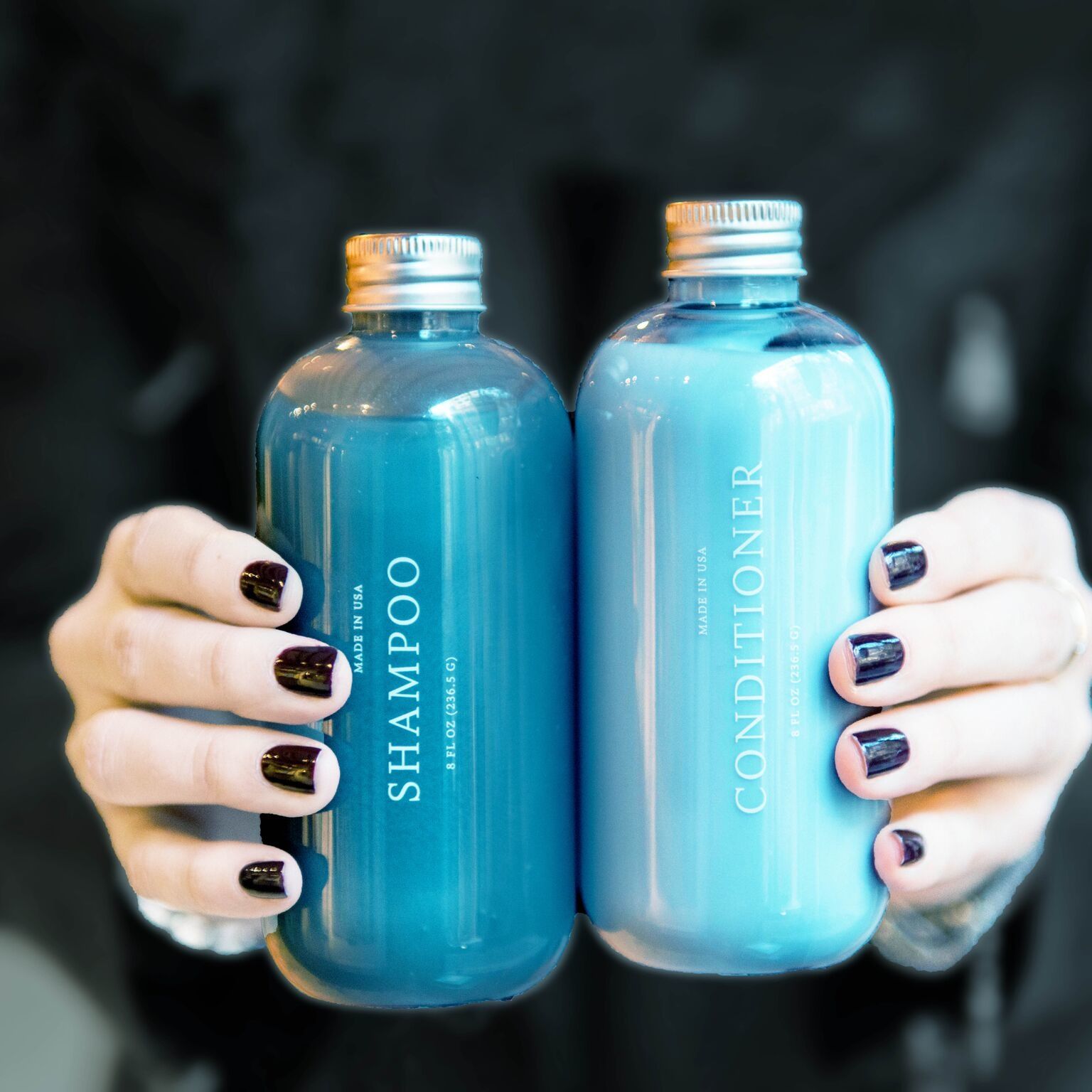 a women holding blue FOB shampoo and conditioner bottles