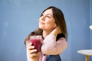 woman drinking smoothie against a blue backdrop
