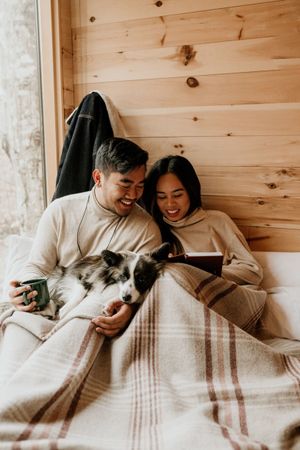A young couple and their dog read a book in a beautiful cabin