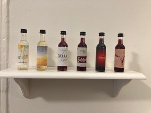 6 tiny bottles of wine on a white shelf