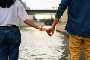 couple holding hands walking along a water side