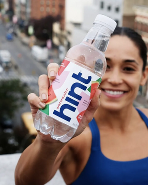 woman holding hint watermelon water bottle up to the camera
